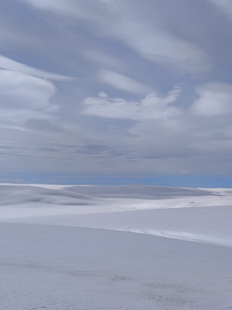Étendue blanche immaculée de neige sous un ciel nuageux, typique d’un paysage traversé lors d’un raid motoneige en région polaire