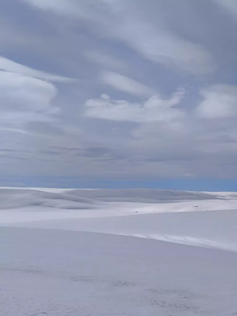 Étendue blanche immaculée de neige sous un ciel nuageux, typique d’un paysage traversé lors d’un raid motoneige en région polaire